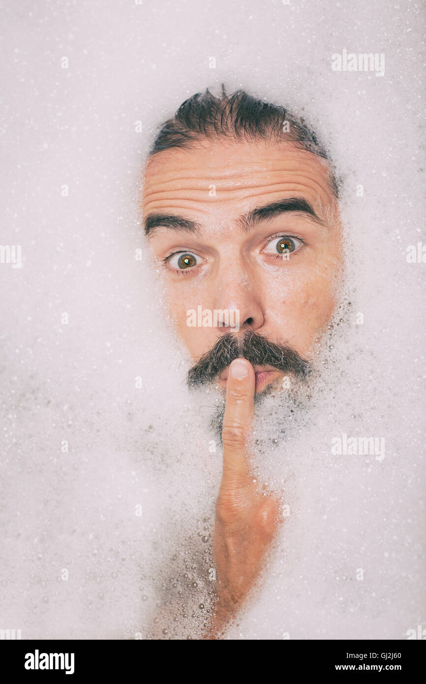 Man with moustache covered in bubbles finger on lips Stock Photo