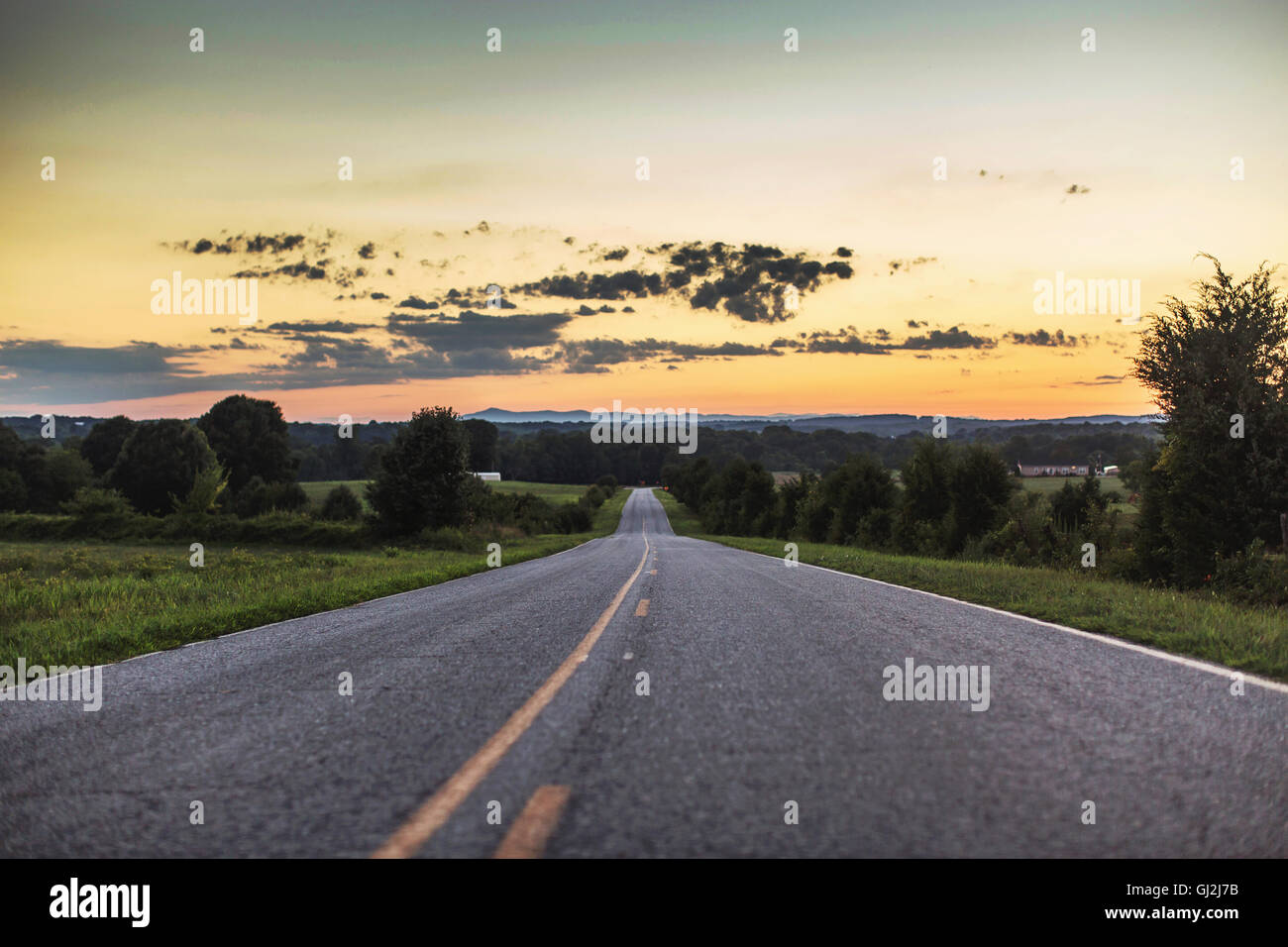 Diminishing perspective of rural road at sunset Stock Photo