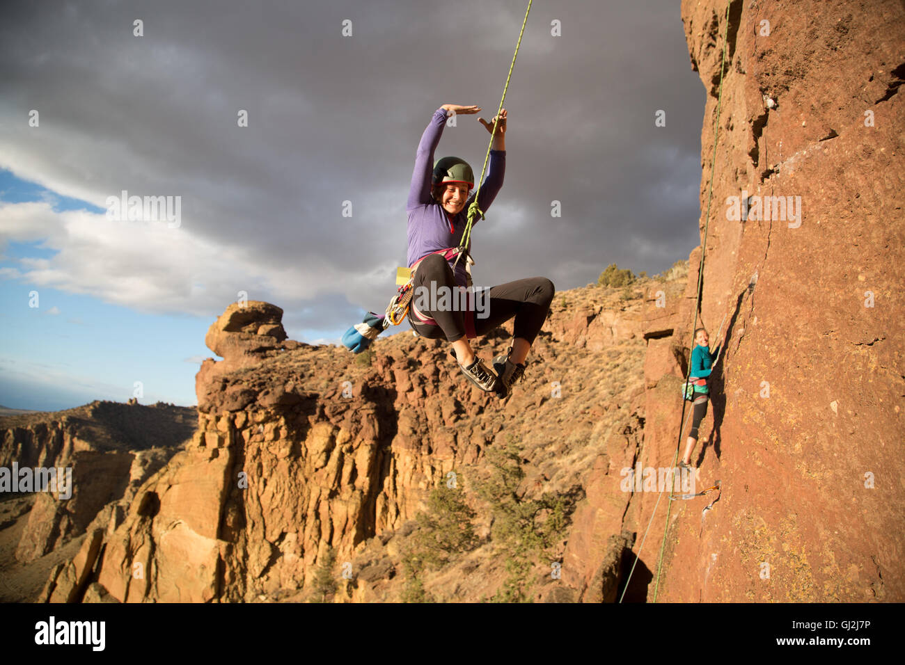 Woman rock climbing swinging on climbing rope Stock Photo