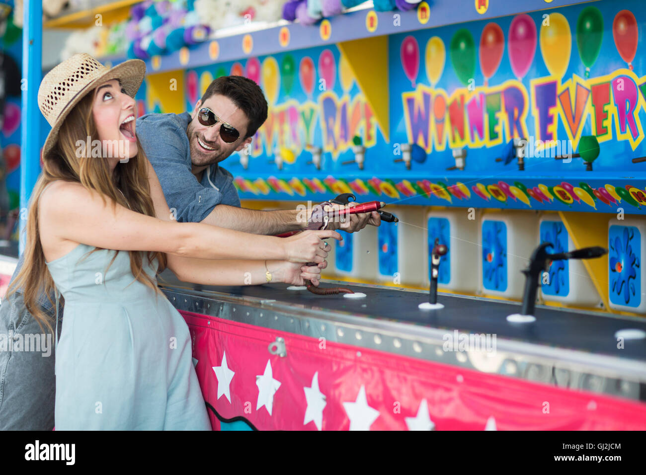 Couple at fairground shooting gallery, Coney island, Brooklyn, New York, USA Stock Photo