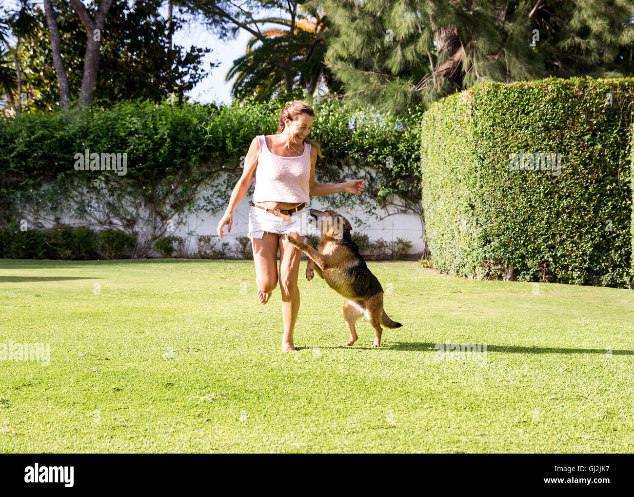 Mature woman running in park with dog Stock Photo