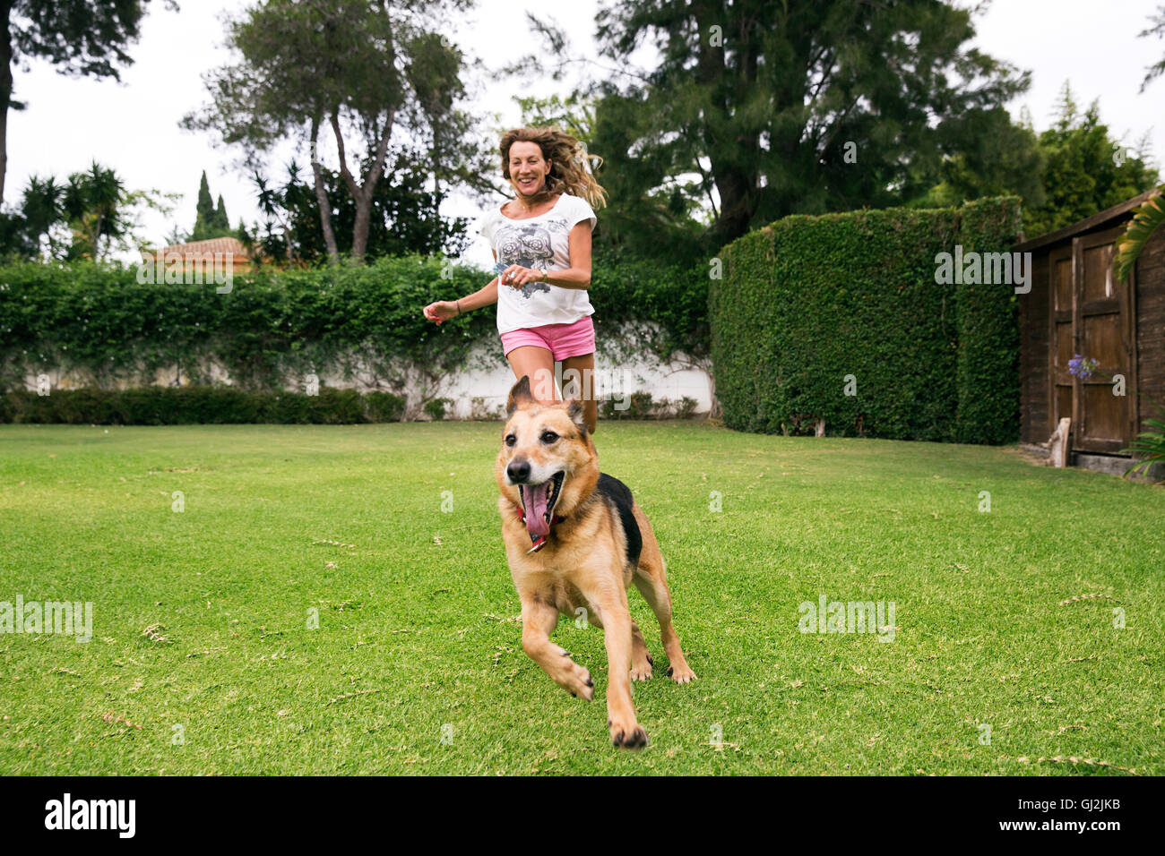 Mature woman running in park with dog Stock Photo