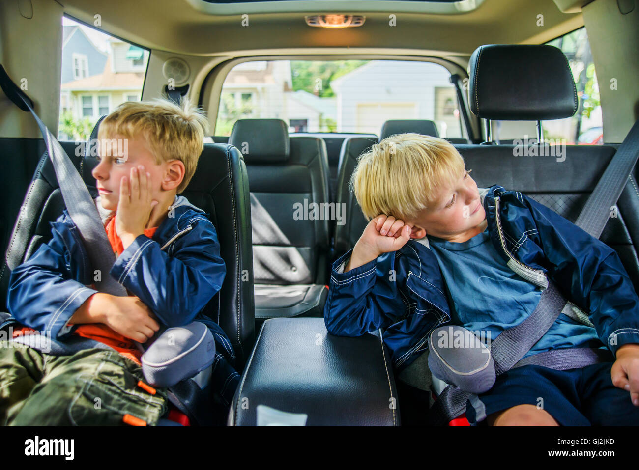 Twin brothers sitting in back of vehicle, bored expressions Stock Photo