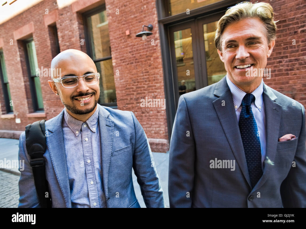 Two businessmen walking together in street, smiling Stock Photo - Alamy