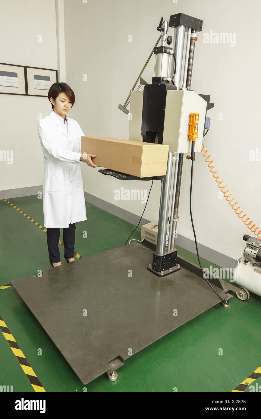Female technician placing cardboard box on packaging machine in