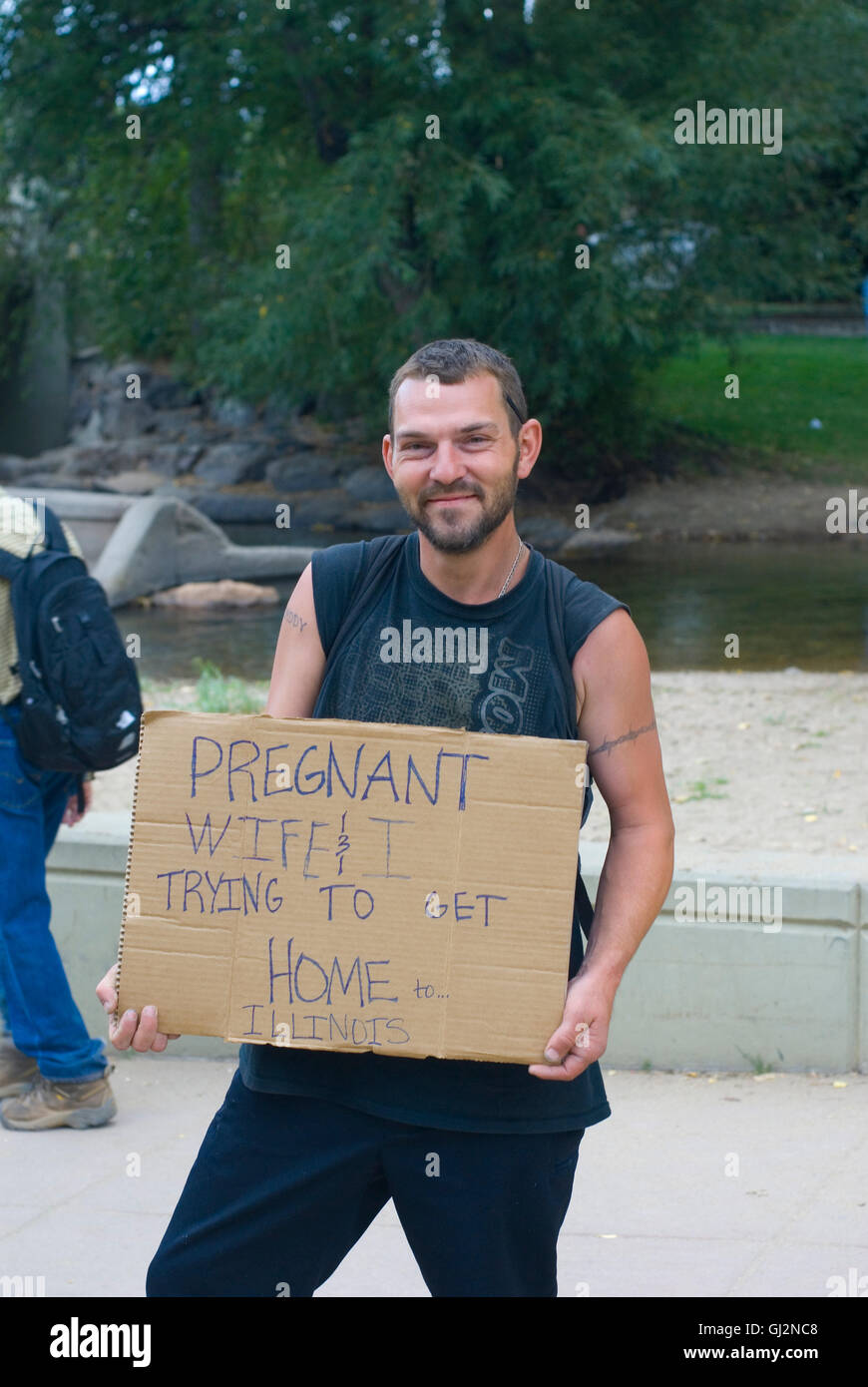 Young man asks for financial help getting home. Sign says he and his pregnant wife trying to get home to Illinois. Boulder Creek Stock Photo