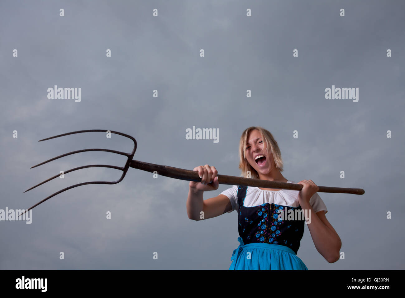 angry bavarian girl with a pitchfork Stock Photo Alamy