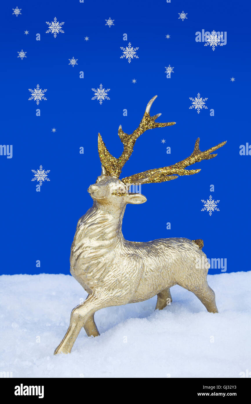 Gold Reindeer Christmas Ornament standing on fake snow with Snow Stock Photo