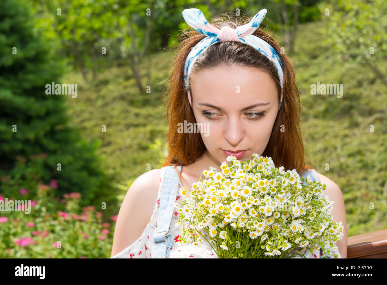 Portrait of a pensive young girl smelling flowers and dreaming while