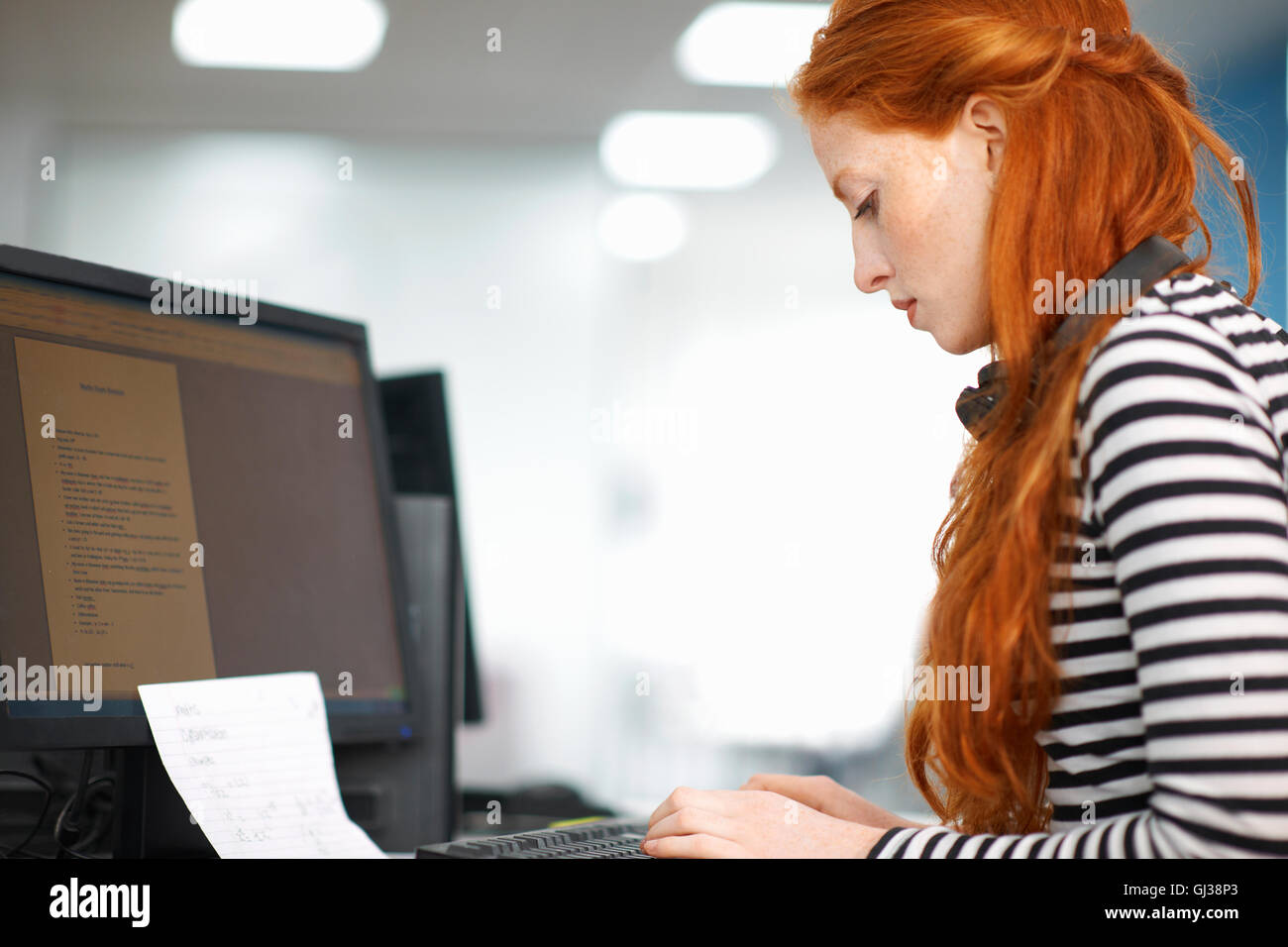Young female college student typing at computer desk Stock Photo