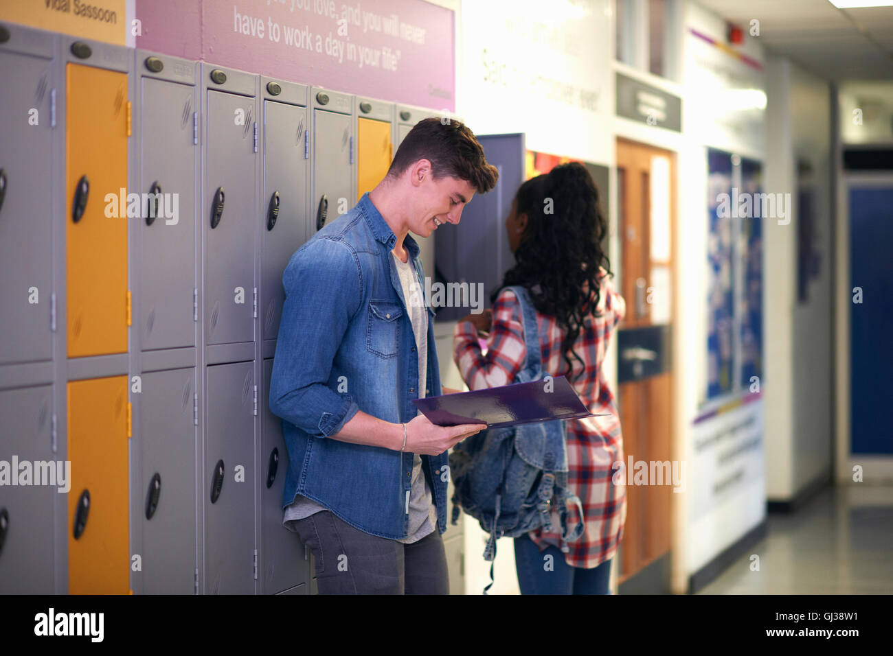 Young male student revising from file in college locker room Stock Photo