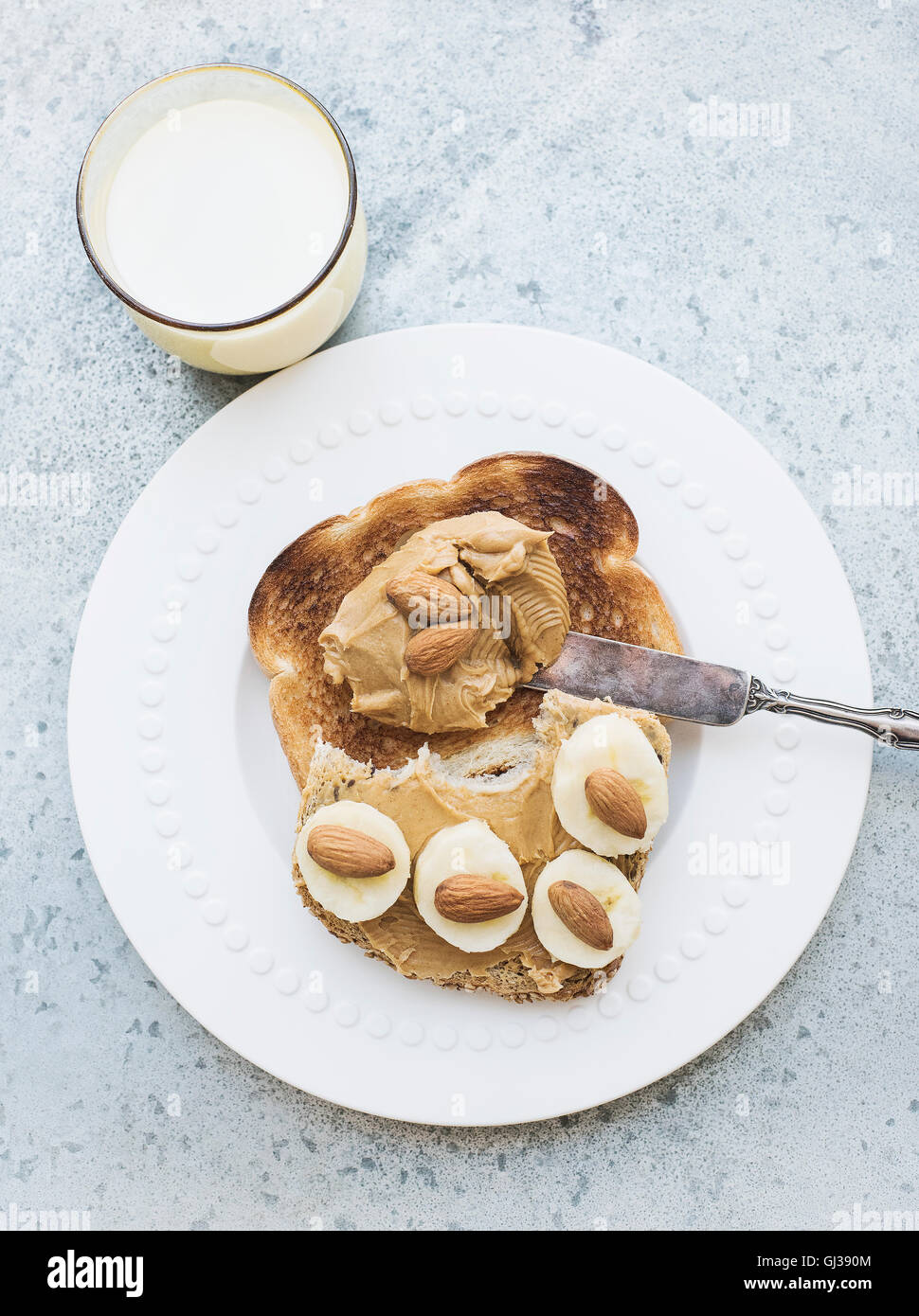 Overhead view of toast with almond butter, banana and milk Stock Photo
