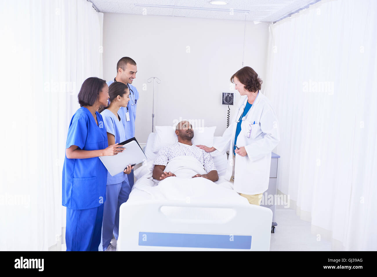 Doctors and nurses surrounding patient in hospital bed Stock Photo