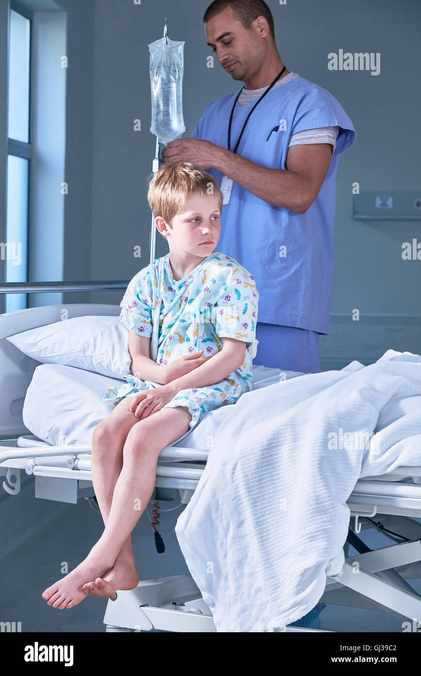 Male nurse adjusting boy patients intravenous drip in hospital children's ward Stock Photo
