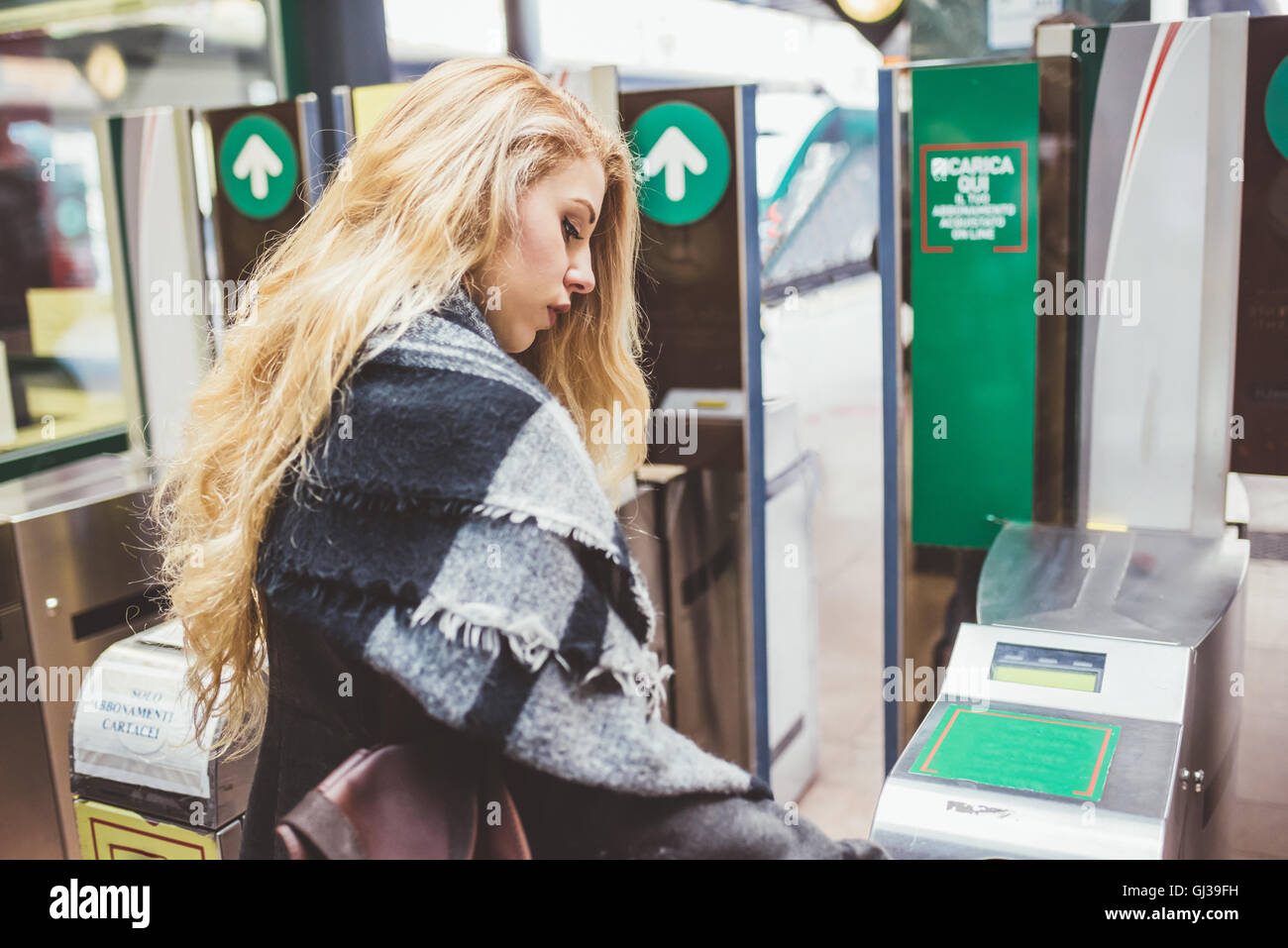 Young woman using ticket barrier in train station Stock Photo - Alamy