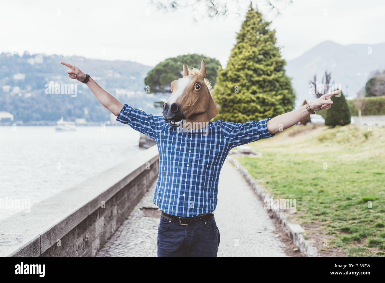 Portrait of man wearing horse mask with arms open, Lake Como, Italy