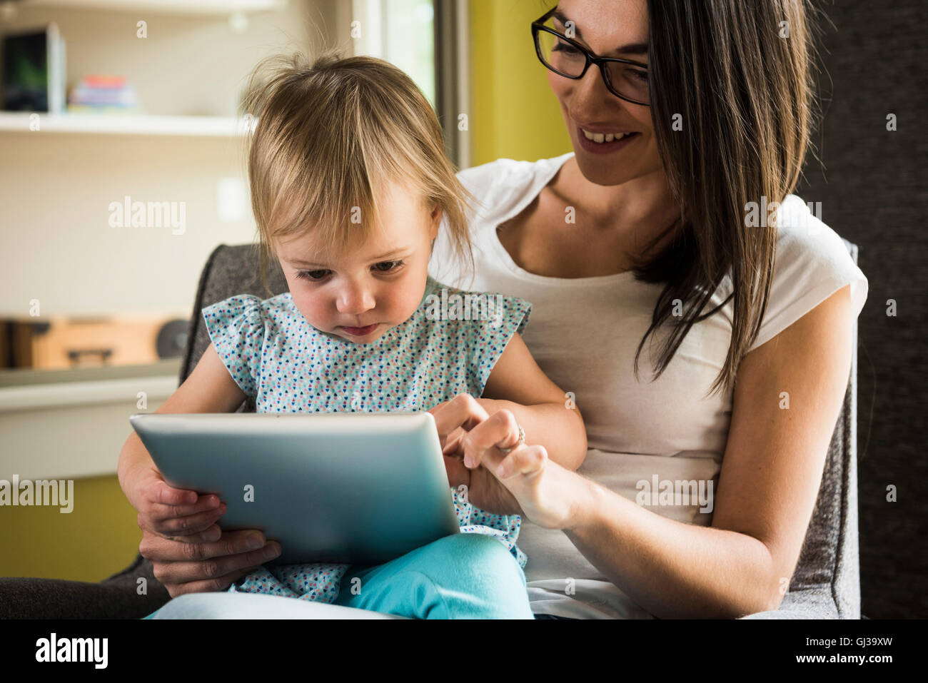 Mother teaching daughter to use digital tablet at home Stock Photo Alamy