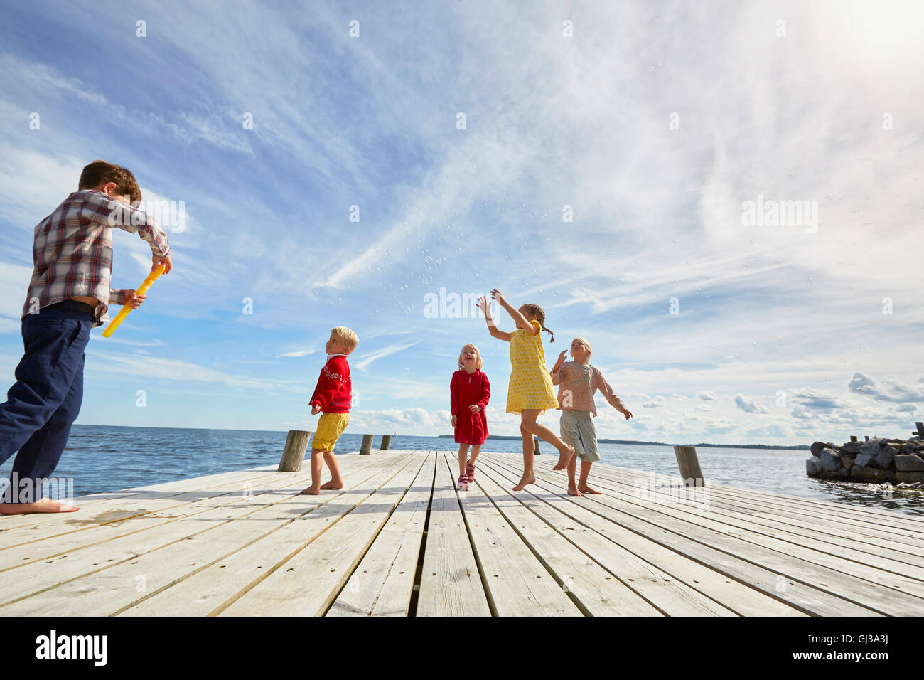 Group of young friends playing on wooden pier Stock Photo