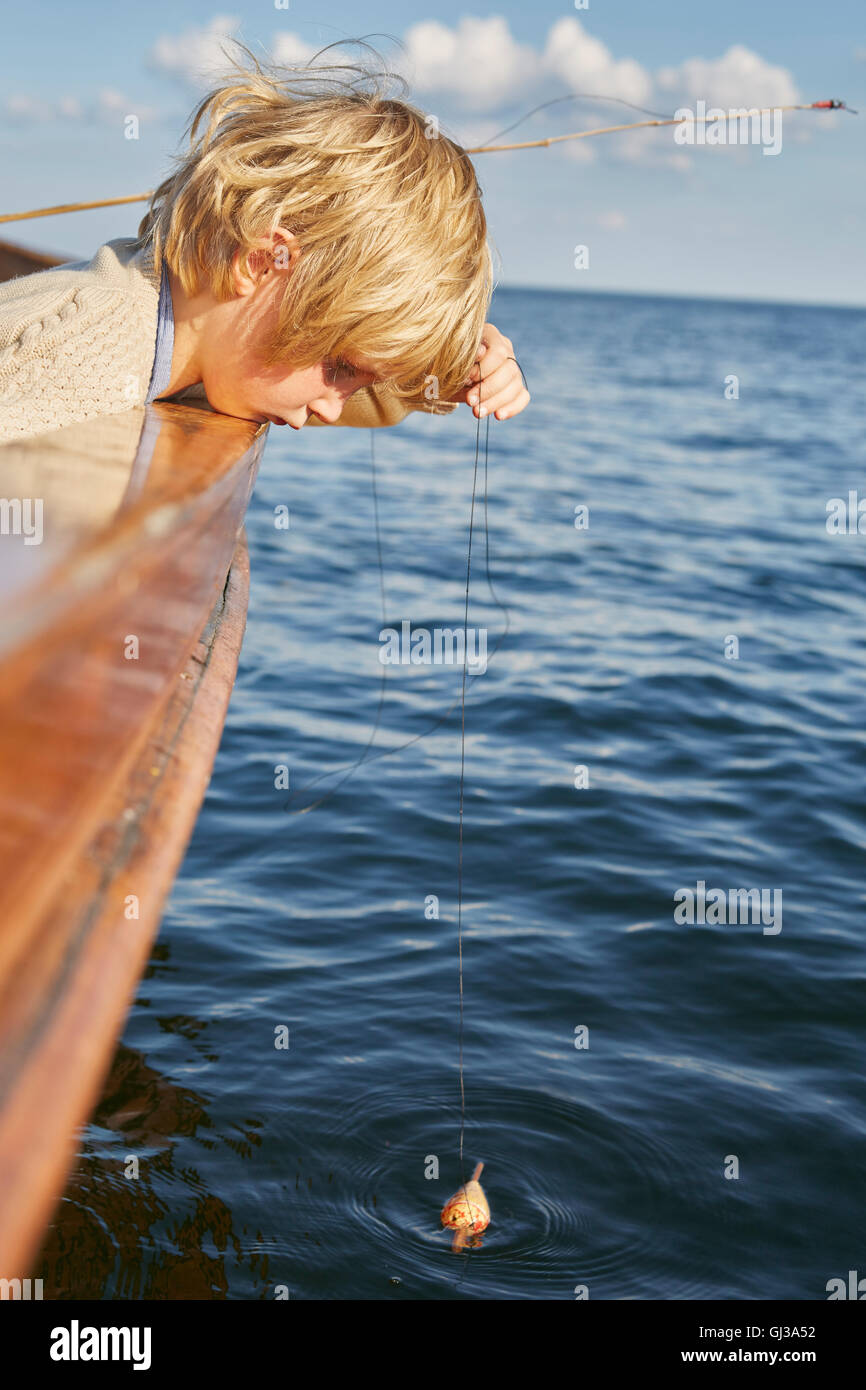 Boy dangling fishing float from boat Stock Photo