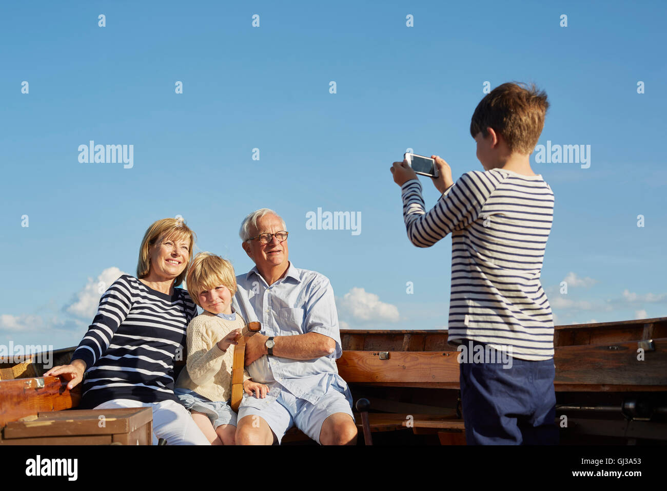 Boy photographing grandparents and brother on boat Stock Photo