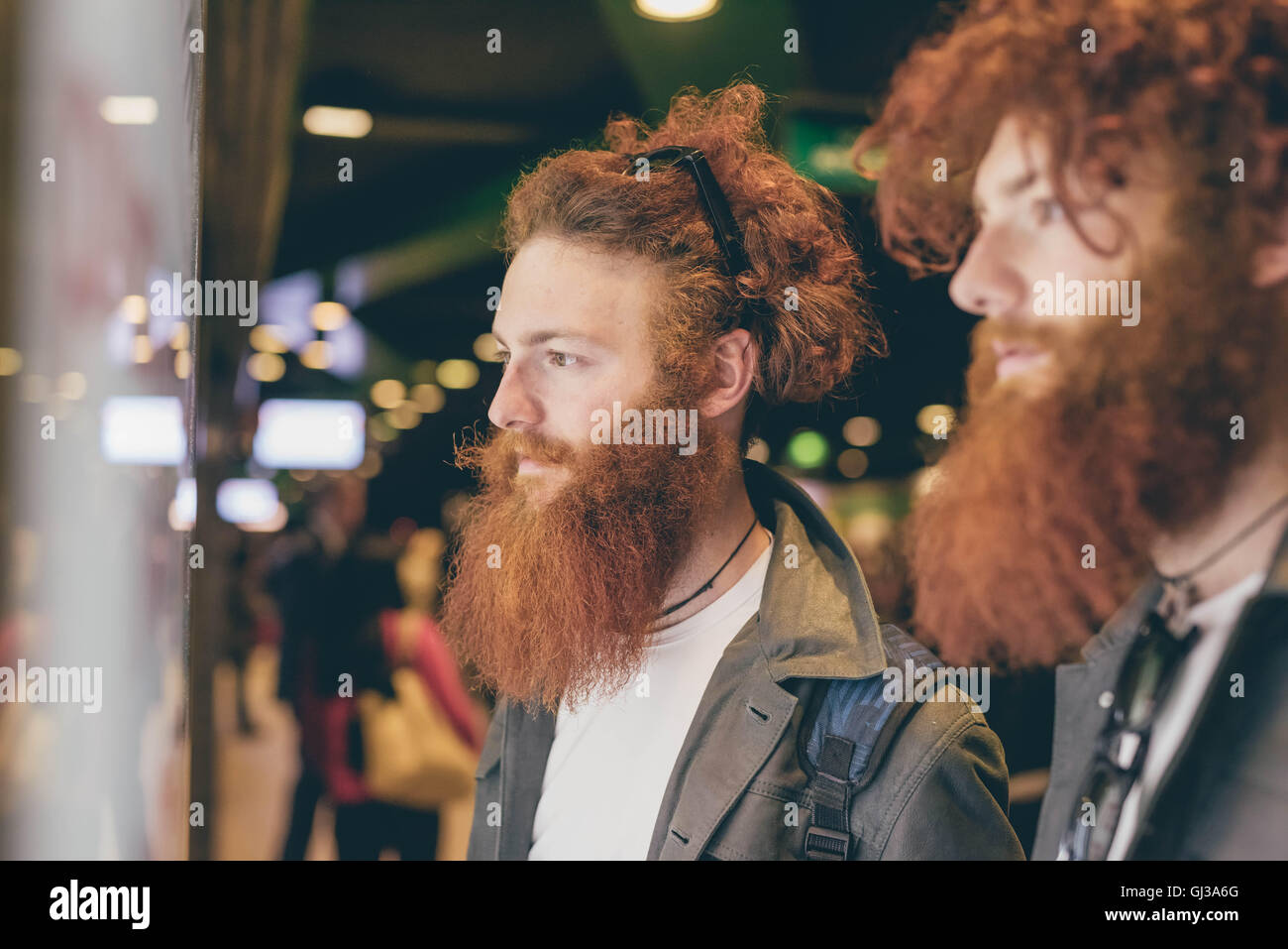 Young male hipster twins with red hair and beards window shopping at night Stock Photo