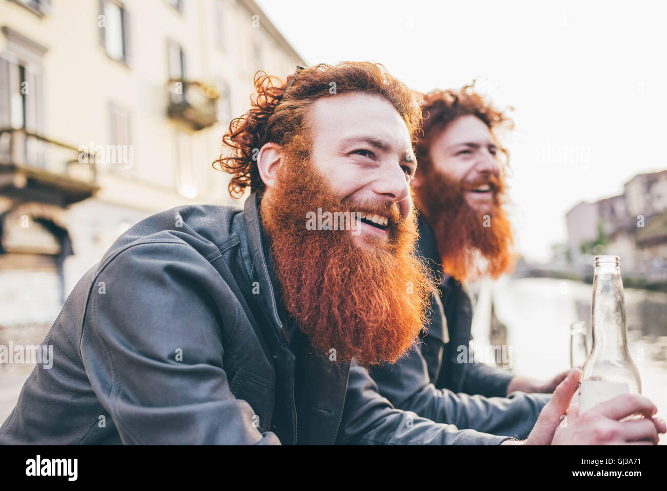 Young male hipster twins with red hair and beards on canal waterfront Stock Photo