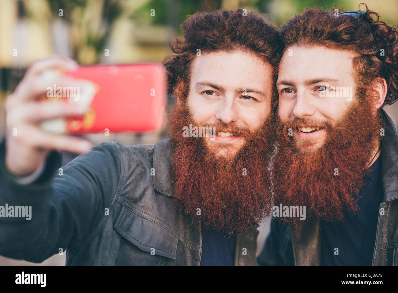 Young male hipster twins with red hair and beards taking smartphone selfie Stock Photo