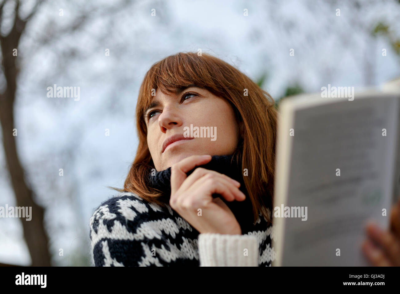 Woman holding book looking away Stock Photo