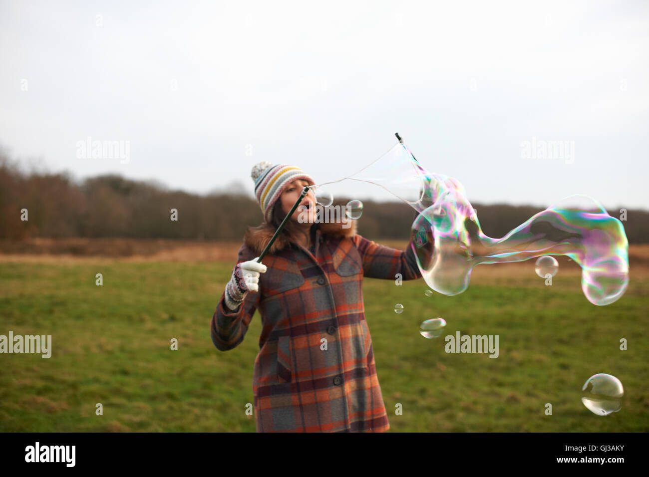 Woman in field using bubble wands to make bubbles Stock Photo