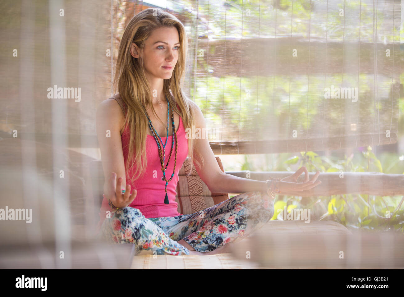 Young woman practising yoga lotus position in porch Stock Photo