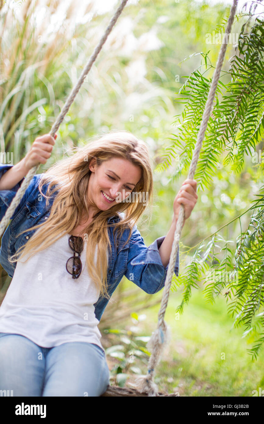 Happy young woman swinging on garden swing Stock Photo