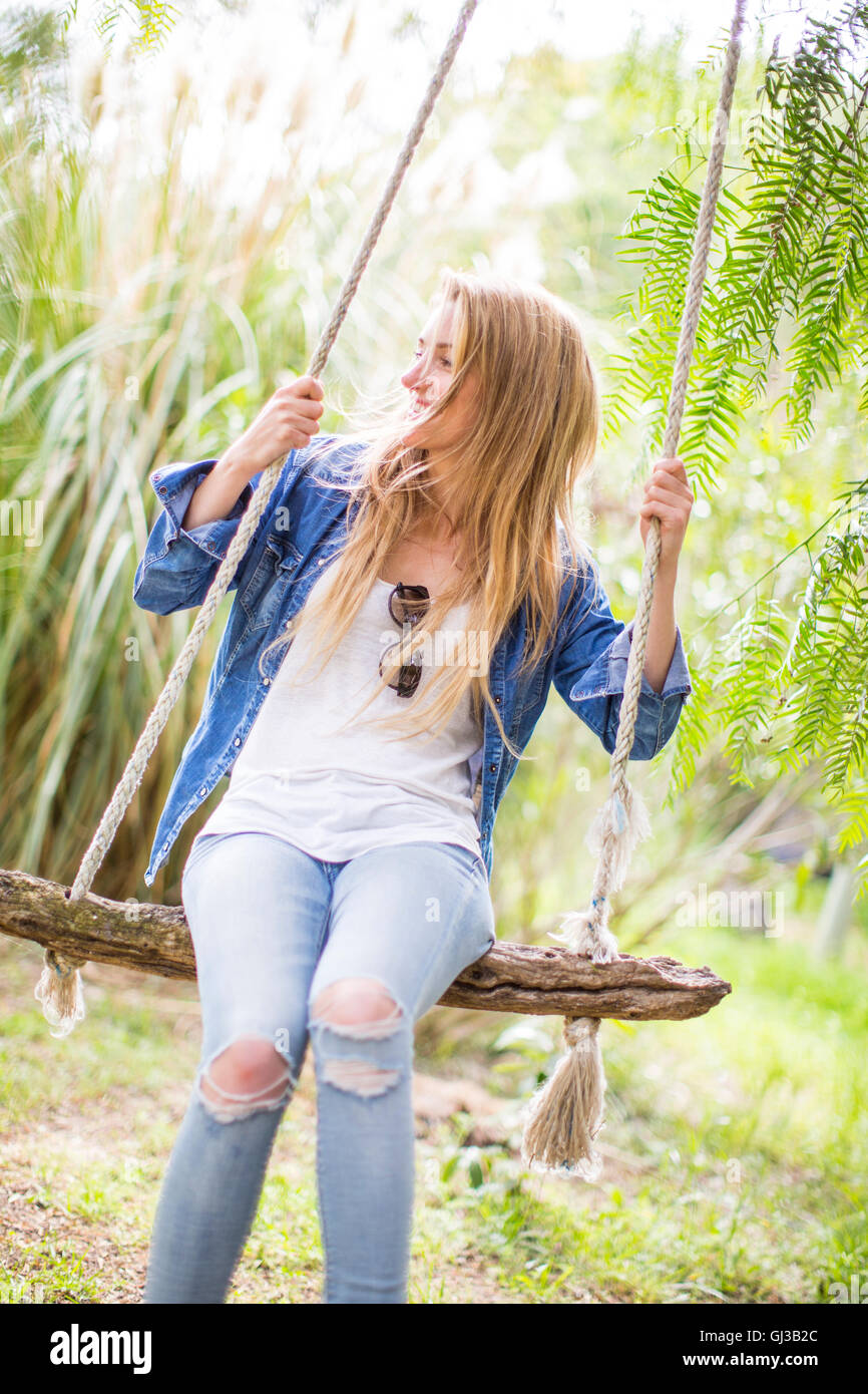 Happy young woman swinging on garden swing Stock Photo