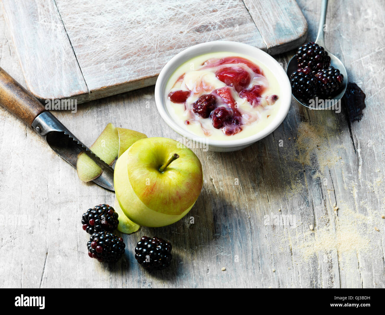 Apple with skin peeled, blackberries, apple and blackberry custard, white washed and scratched wooden surface Stock Photo