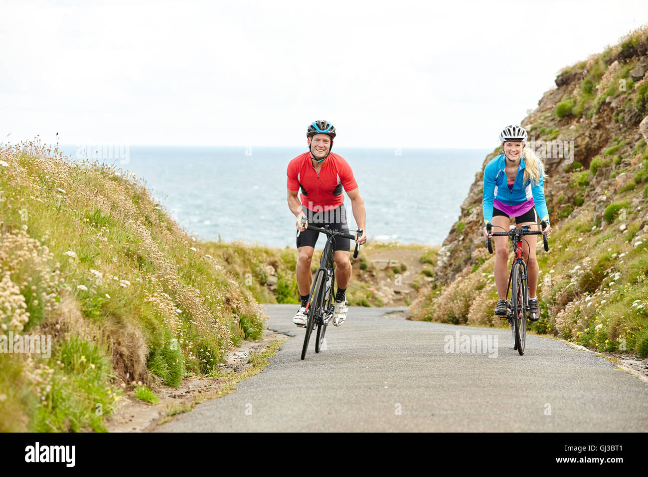 Cyclists riding on road overlooking ocean Stock Photo