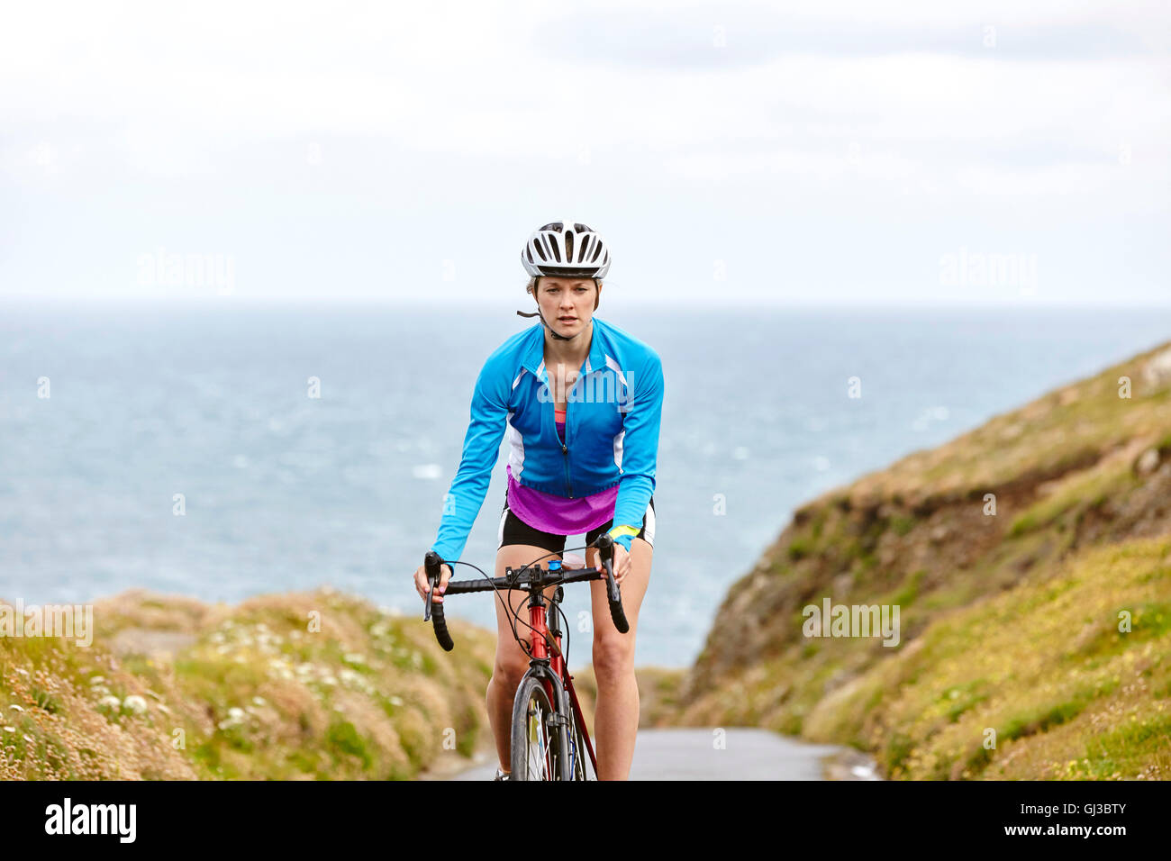 Cyclist riding on road overlooking ocean Stock Photo