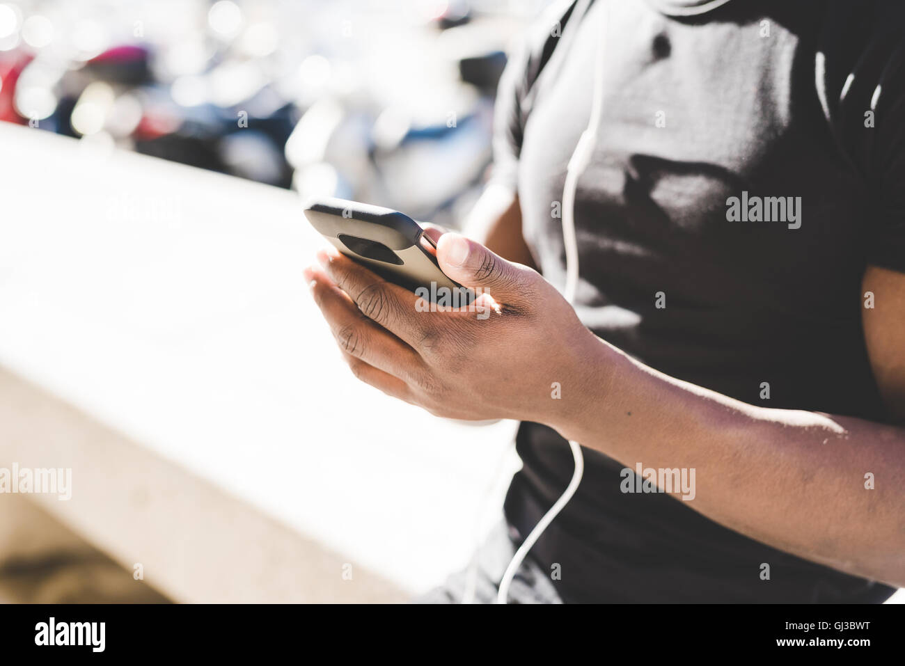 Young man outdoors, holding smartphone, mid section Stock Photo