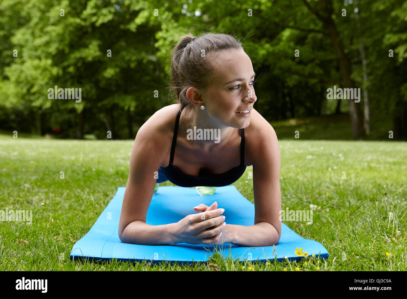 Young woman training in park, doing push ups on exercise mat Stock Photo