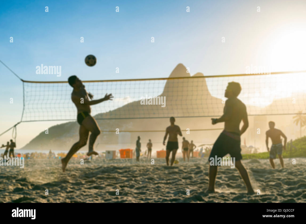 Defocused scene of silhouettes of carioca Brazilians playing futevolei (footvolley) against a sunset backdrop of Ipanema Beach Stock Photo