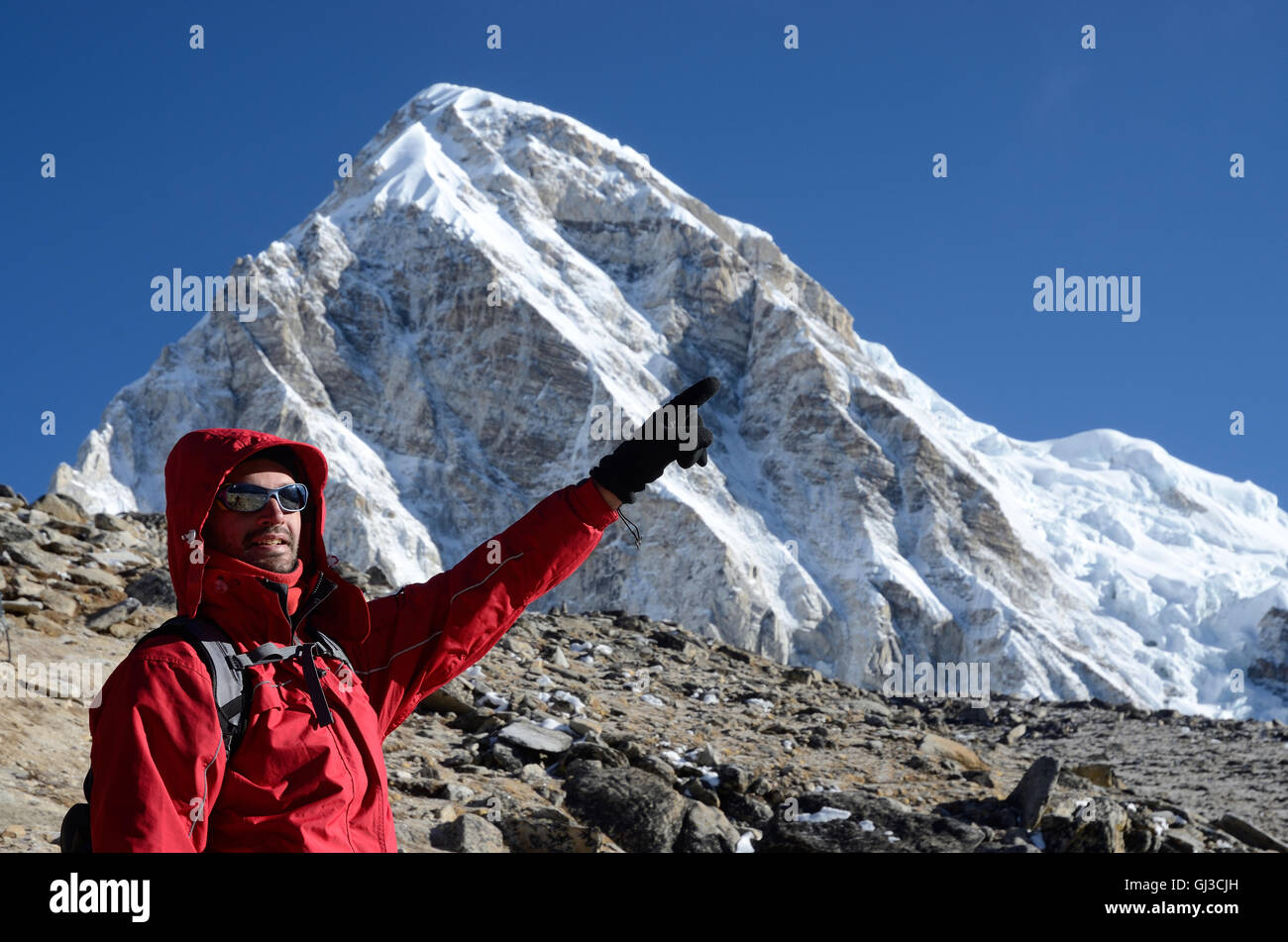 Young mountain climber standing near Kala Patthar mountain and showing to Everest summit Stock Photo