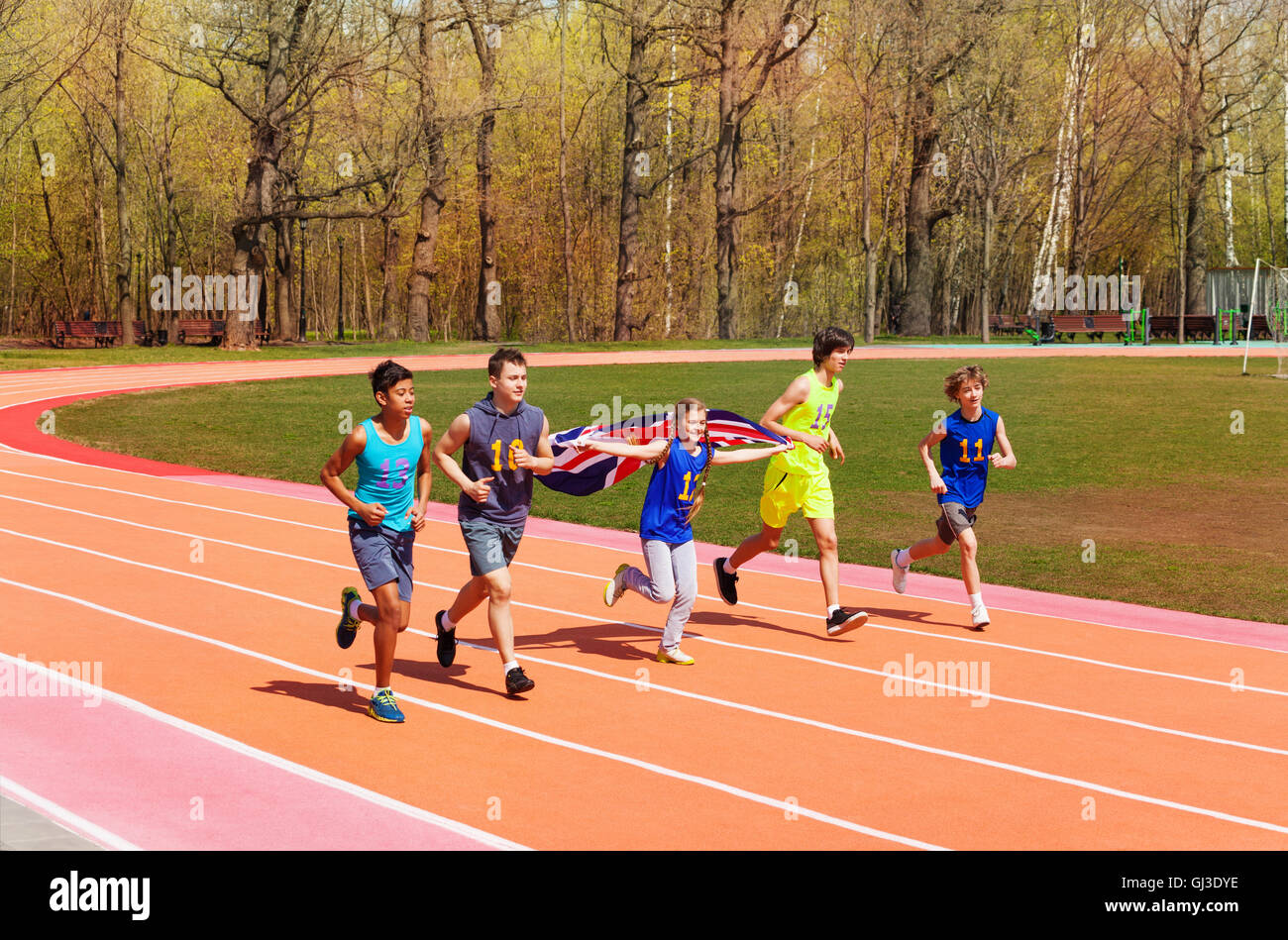 Teenage track sprinters running with British flag Stock Photo