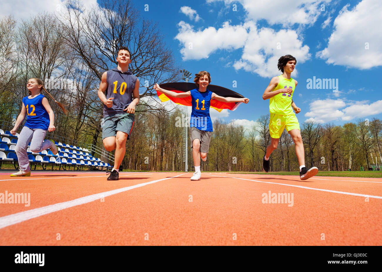 Teenage athletes with German flag running on track Stock Photo