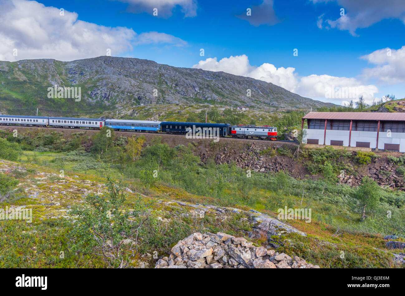 Silver and red locomotive train pulling carriages towards Bjornfell Station and Norway Swedish border Stock Photo