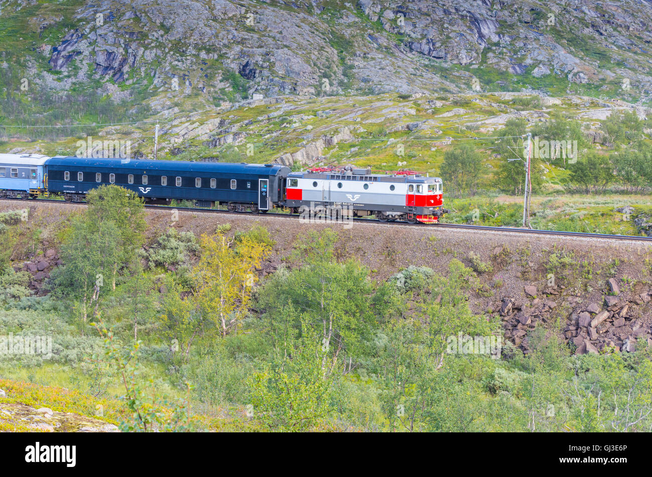 Silver and red locomotive train pulling carriages towards Bjornfell Station and Norway Swedish border Stock Photo