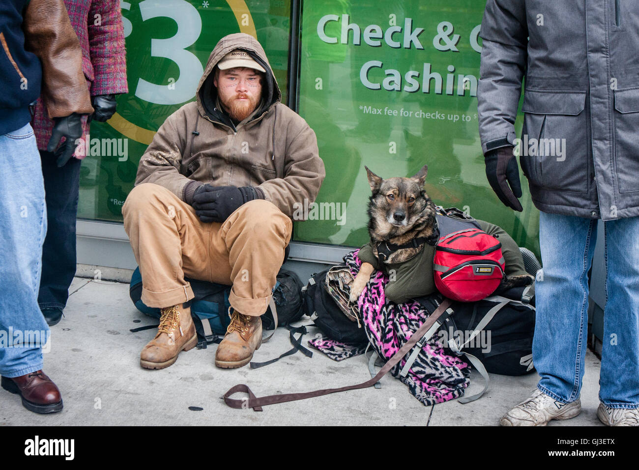 Chicago, Illinois - November 28, 2014: A Chicago homeless man and his dog sit on the sidewalk on a frigid cold day in late November. Stock Photo