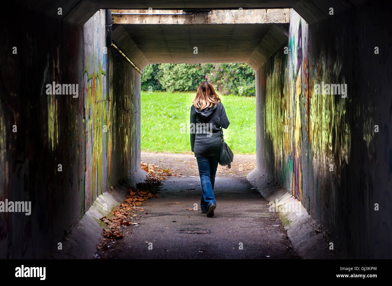 woman walk alone through a dangerous and dark underpass Stock Photo
