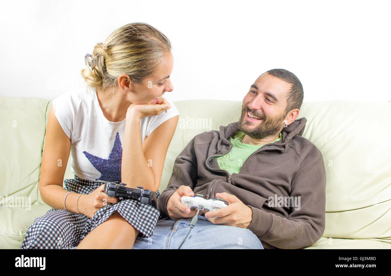 fun couple look at each other as they play video games on the couch