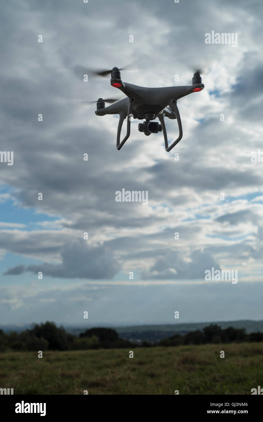 Silhouette of a DJI Phantom 4 quadcopter drone against a cloudy sky Stock Photo