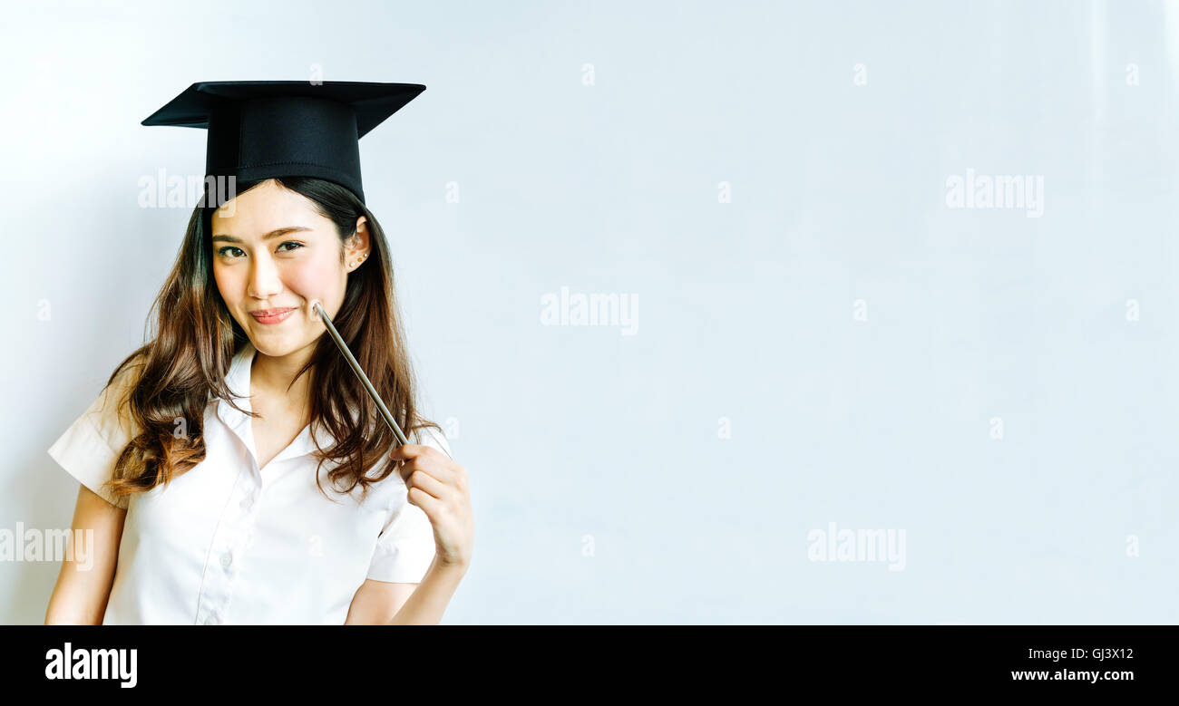 Beautiful asian university or college graduate student woman wearing mortar board, doing cute pose in front of shiny whiteboard, Stock Photo