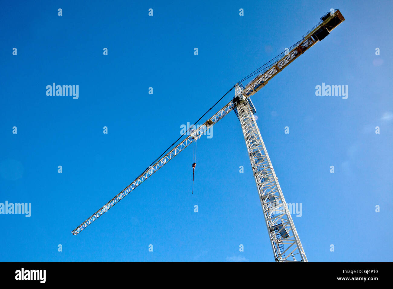 Tower crane raised high into a blue sky background Stock Photo