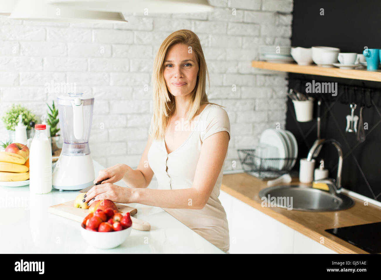 Pretty housewife standing at kitchen table with different fruit Stock Photo